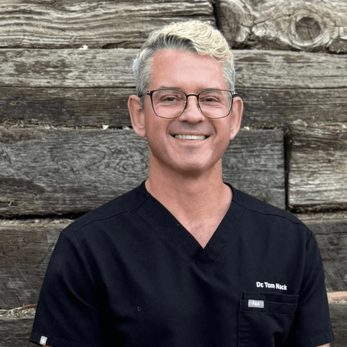 Dr. Tom Nack smiling in black scrubs